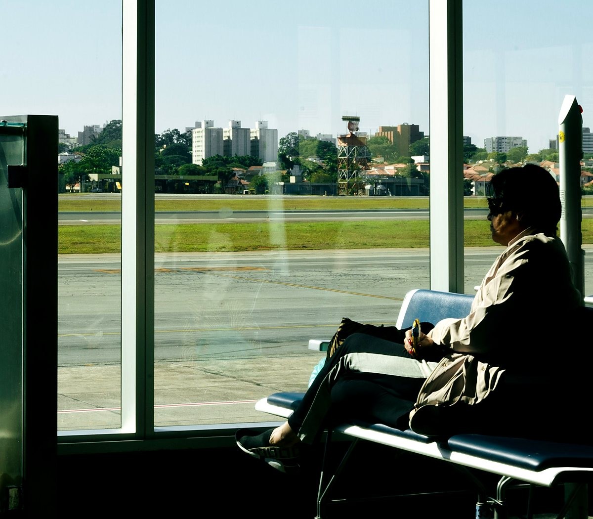 Viajante sentado diante da janela do aeroporto, olhando a pista